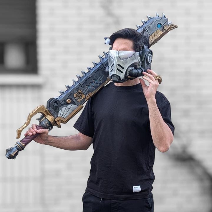 A person wearing a black t-shirt and holding a large, ornate sword-like weapon.
