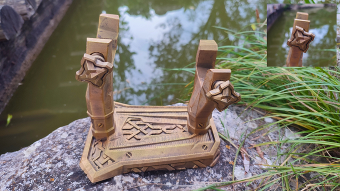 a wooden object with intricate designs, placed on a rock near a body of water.