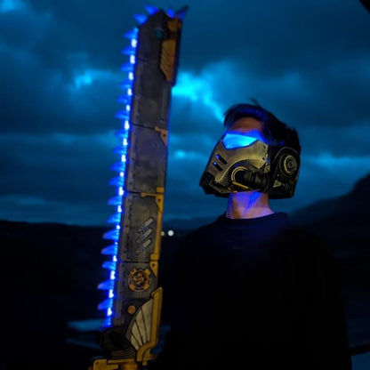 A person wearing a futuristic helmet and holding a large, glowing sword stands in a dark, cloudy environment.