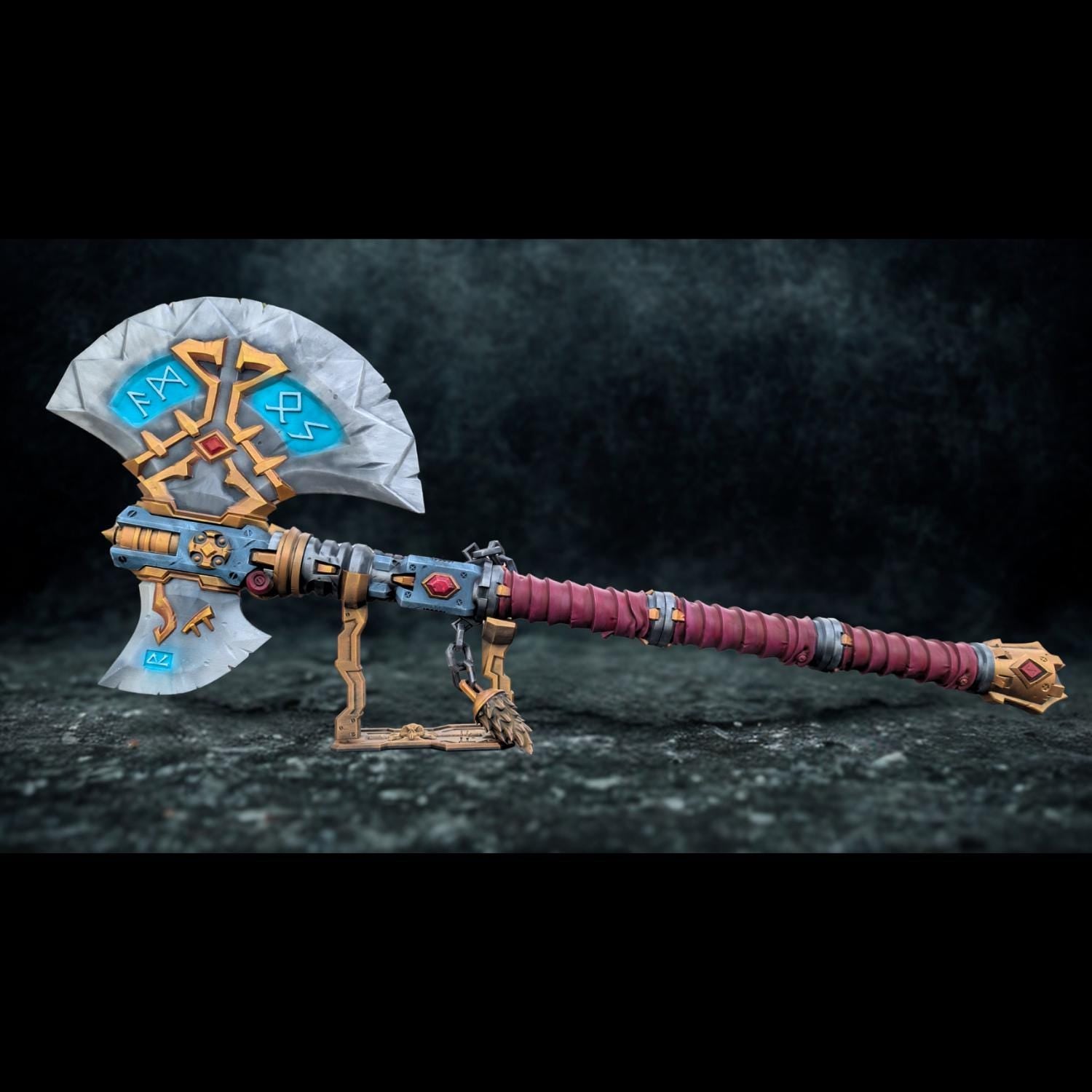 A detailed and ornate fantasy weapon, possibly a sword or axe, with intricate designs and patterns. The weapon appears to be a collectible item or a prop, displayed on a stand against a dark background.