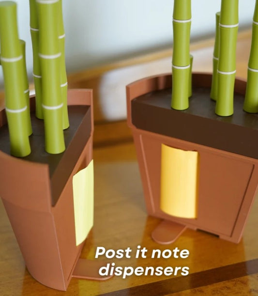 Two brown paper dispensers with green bamboo-like sticks protruding from the top, placed on a wooden surface.