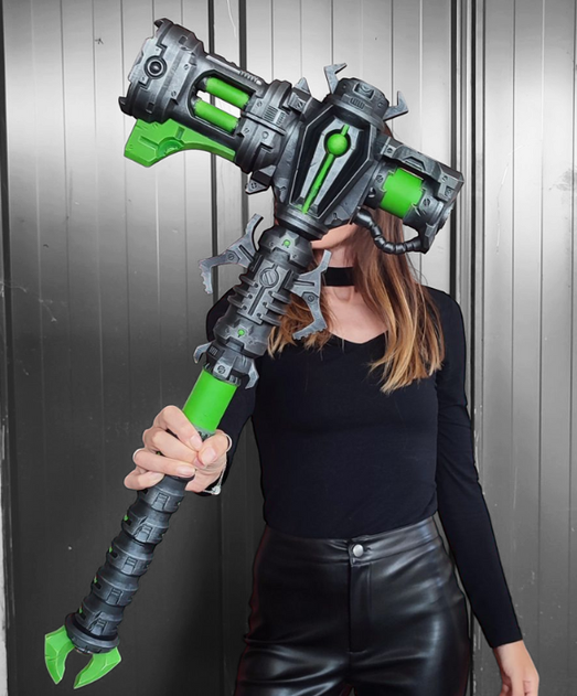 A person is holding a large, futuristic-looking gun with a green and gray color scheme.