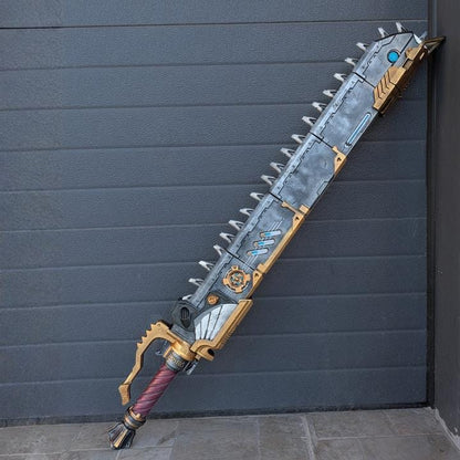 A large, long sword-like weapon with a metallic appearance and various decorative elements, such as spikes and gears, is leaning against a gray wall.