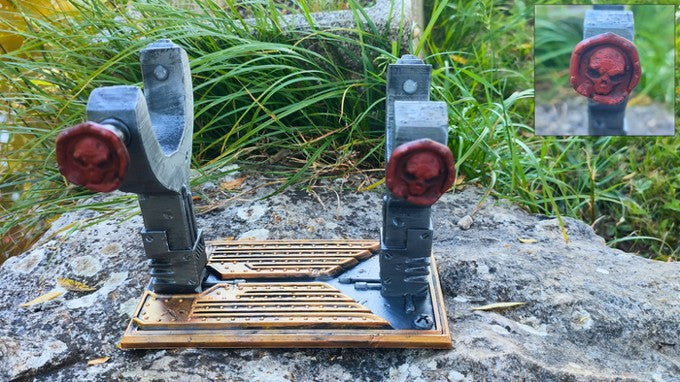 a pair of gray and red slingshots with skull-shaped handles, placed on a wooden base.