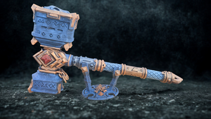 A blue and gold hammer with intricate designs and patterns, displayed on a dark surface.