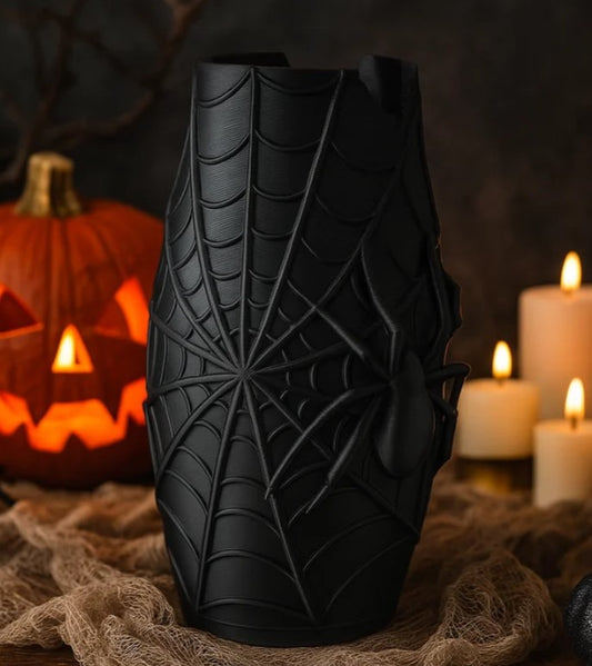 a Halloween-themed scene with a carved pumpkin, a spider web vase, and lit candles.