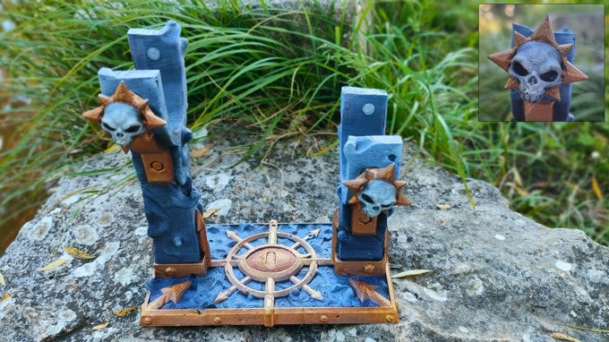 a blue and gold miniature statue of a skull with a star on top, placed on a rock.