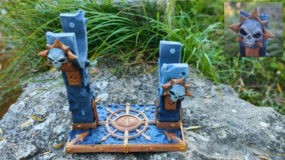 a blue and gold miniature statue of a skull with a star on top, placed on a rock.