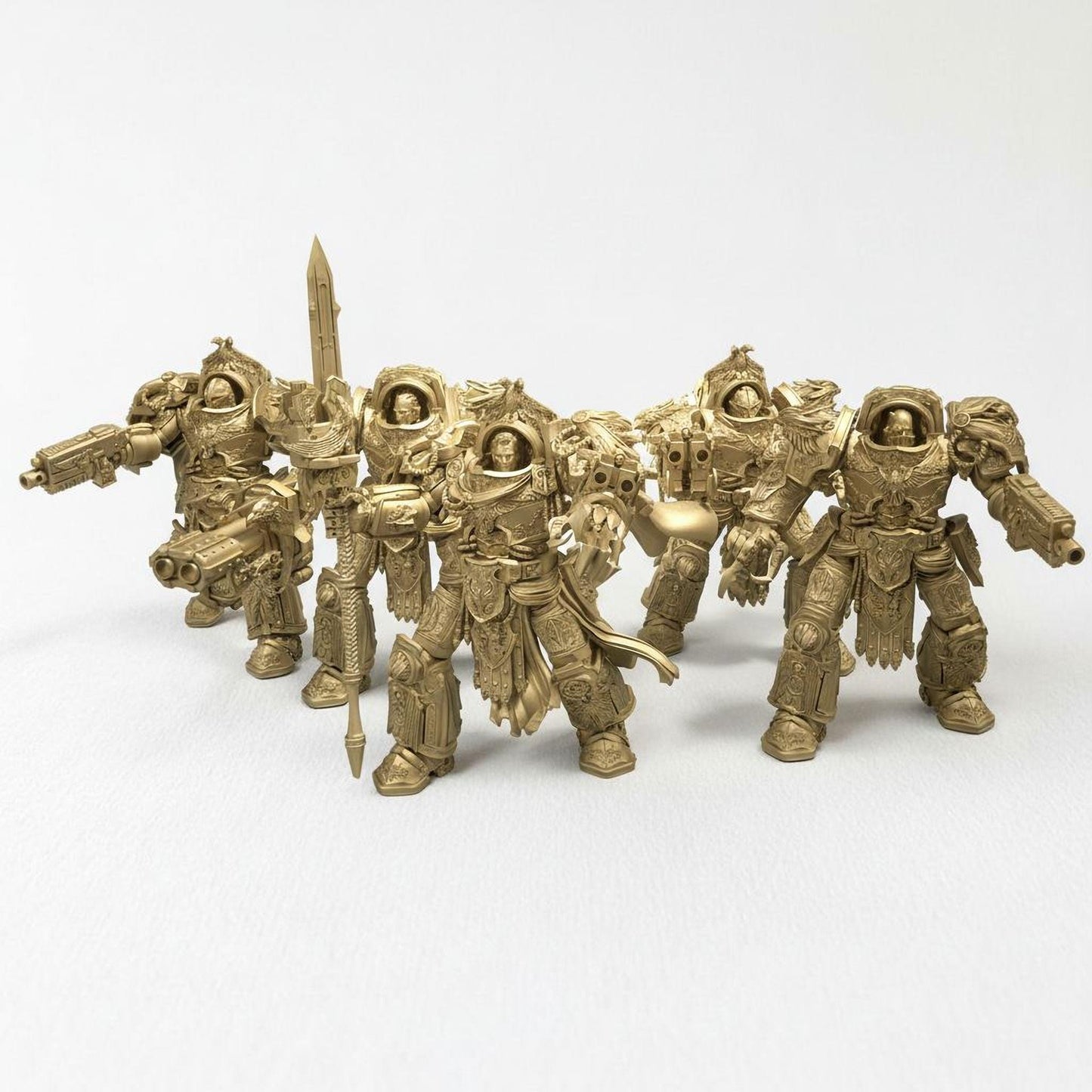 A group of golden-colored figurines of soldiers or fantasy characters, arranged in a row and facing the same direction.