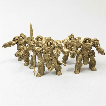 A group of golden-colored figurines of soldiers or fantasy characters, arranged in a row and facing the same direction.