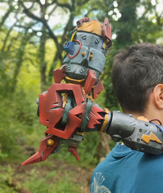 A child is holding a large, colorful toy robot in a forest setting.