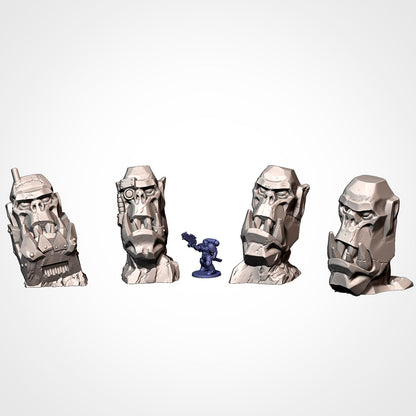 Four distinct Ork head scatter terrain monuments with miniature for scale